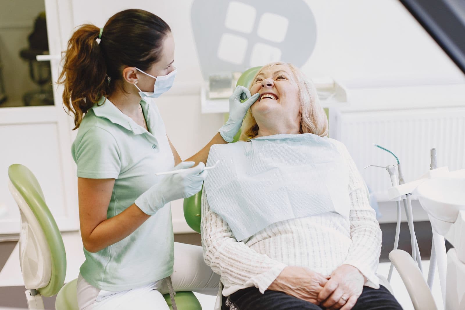 Patient seated in a dental chair with a dentist in scrubs alongside